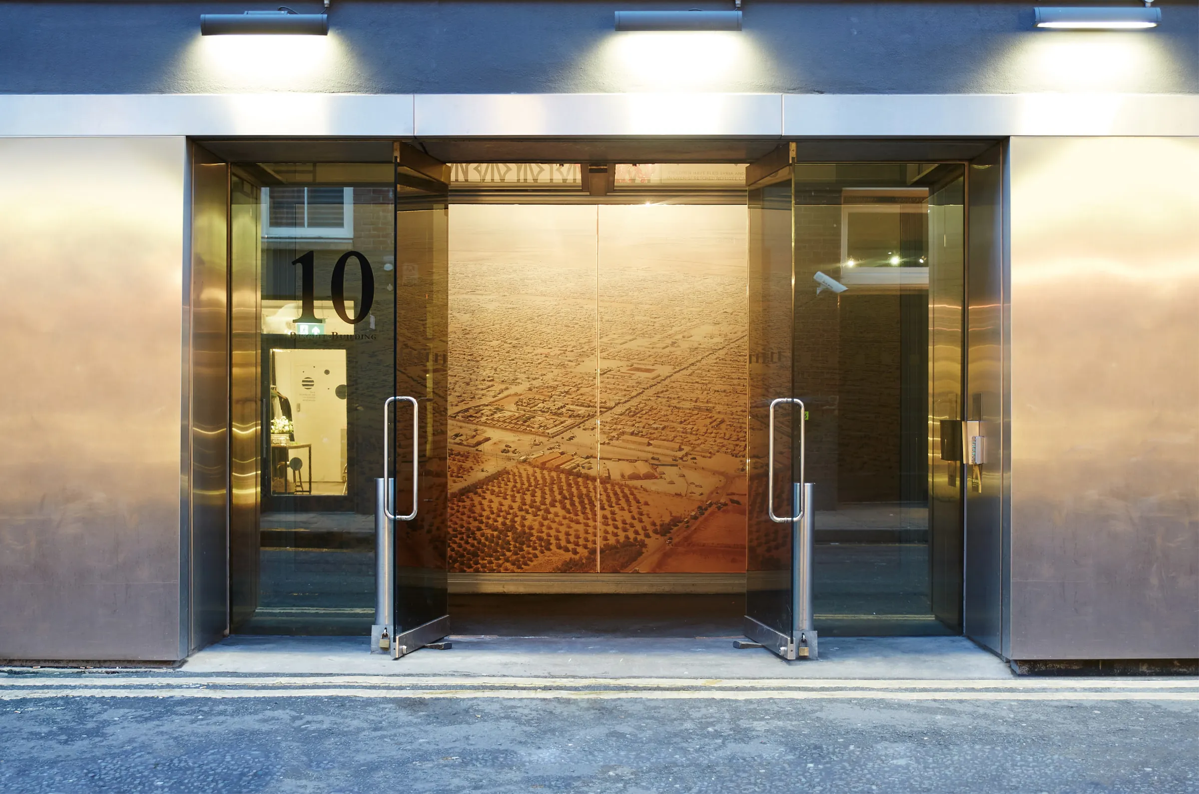 Gallery entrance at number 10, an aerial view of Za'atari printed across the glass doors