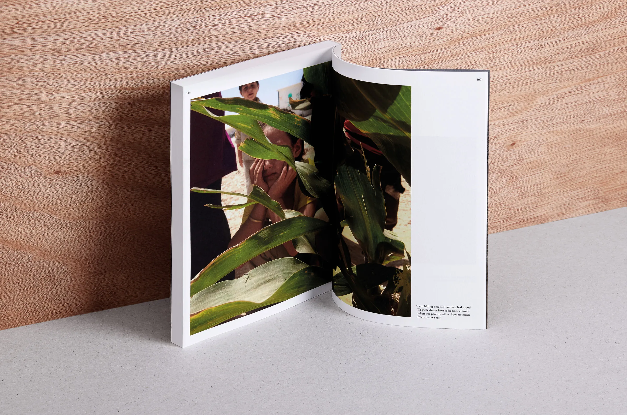 Book spread showing a child's photograph of others half-hidden behind tall leaves