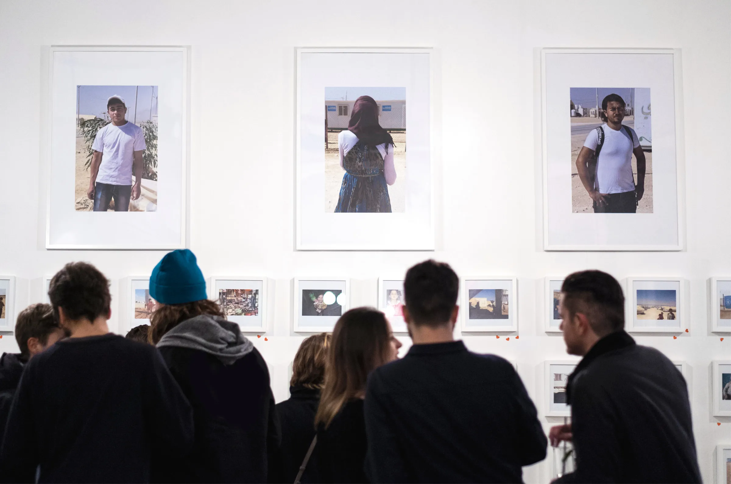 Visitors gathered at the exhibition wall beneath three large portraits