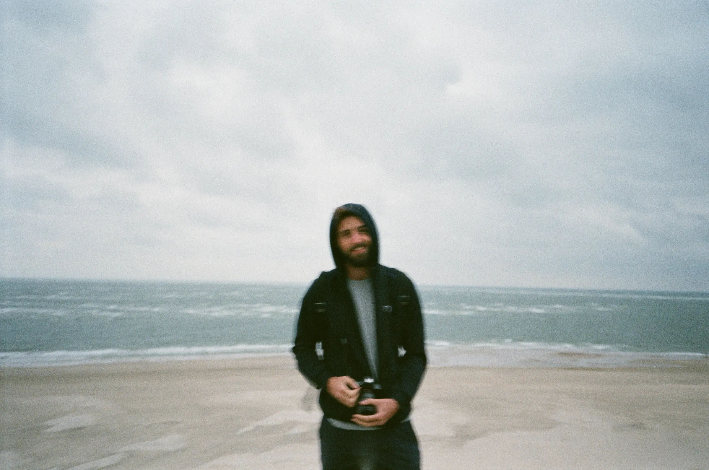 Dominic Nazeri on a beach with a camera, film photograph